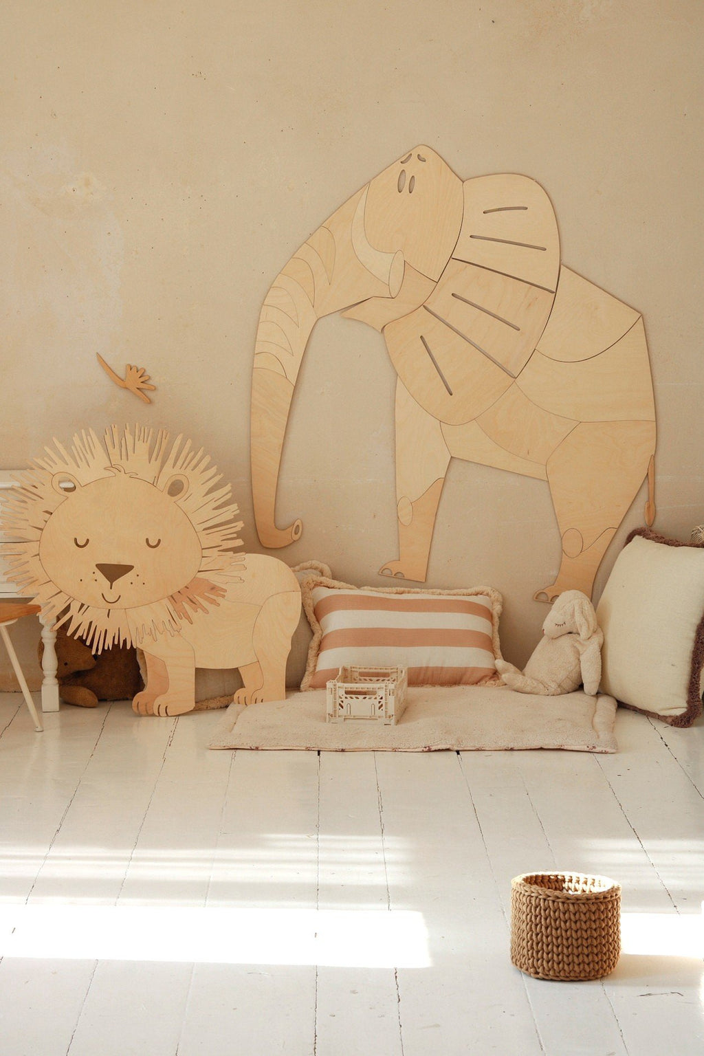 4. Wooden elephant and lion wall decorations in child's room with cushions and toys