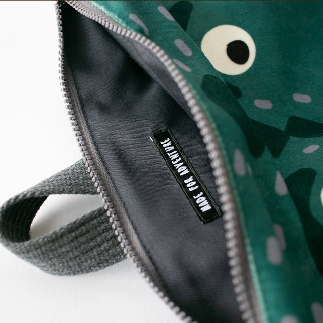 12. Close-up of Muni dinosaur backpack interior with 'Made for Adventure' label