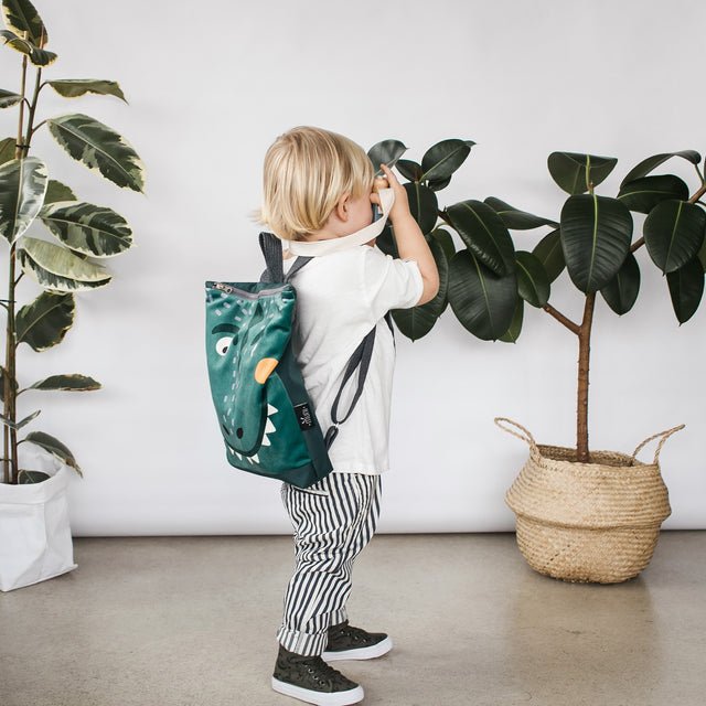 5. Child exploring indoors with Muni dinosaur backpack