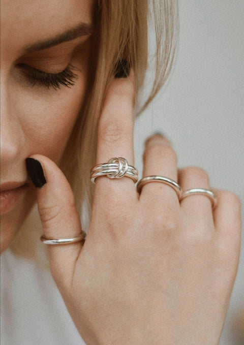 1. Woman wearing NO MORE double ring in silver, styled with other rings for a chic look