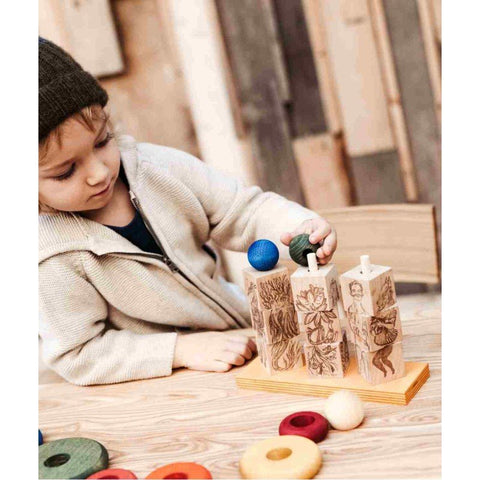 1. Child playing with Wooden Story Dreamland Spinner Puzzle, arranging colorful balls on engraved wooden blocks at a wooden table