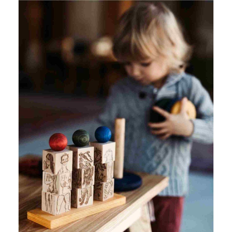 1. Child holding pieces of Wooden Story Dreamland Spinner Puzzle, with focus on stacked blocks and colorful spheres