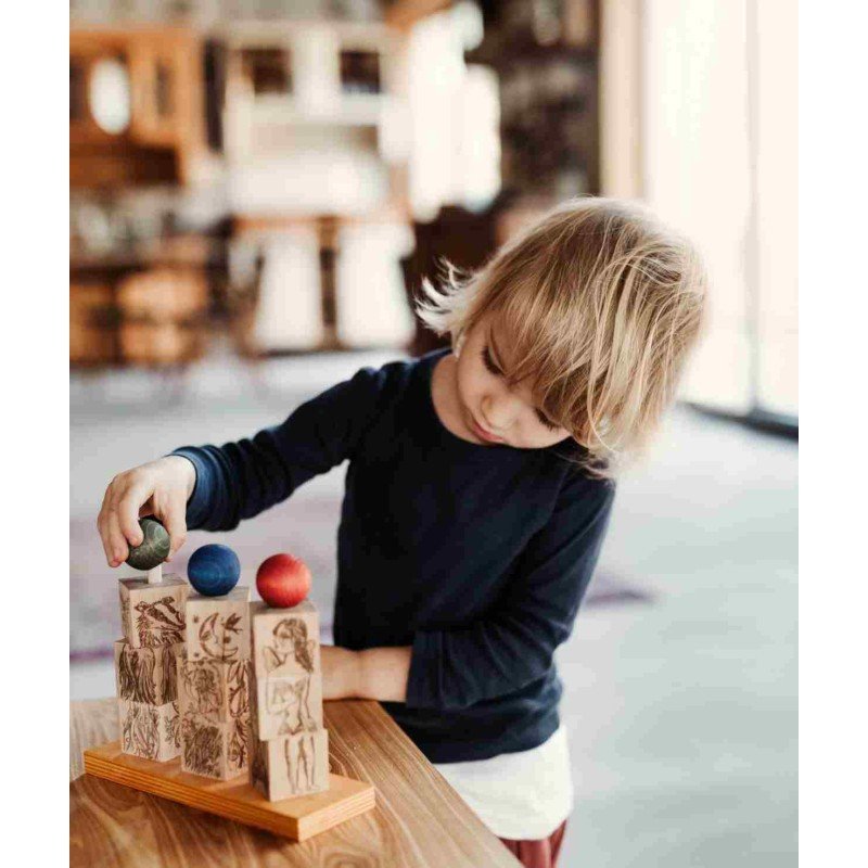 1. Young child interacting with Wooden Story Dreamland Spinner Puzzle, stacking blocks with colorful spheres in a cozy room