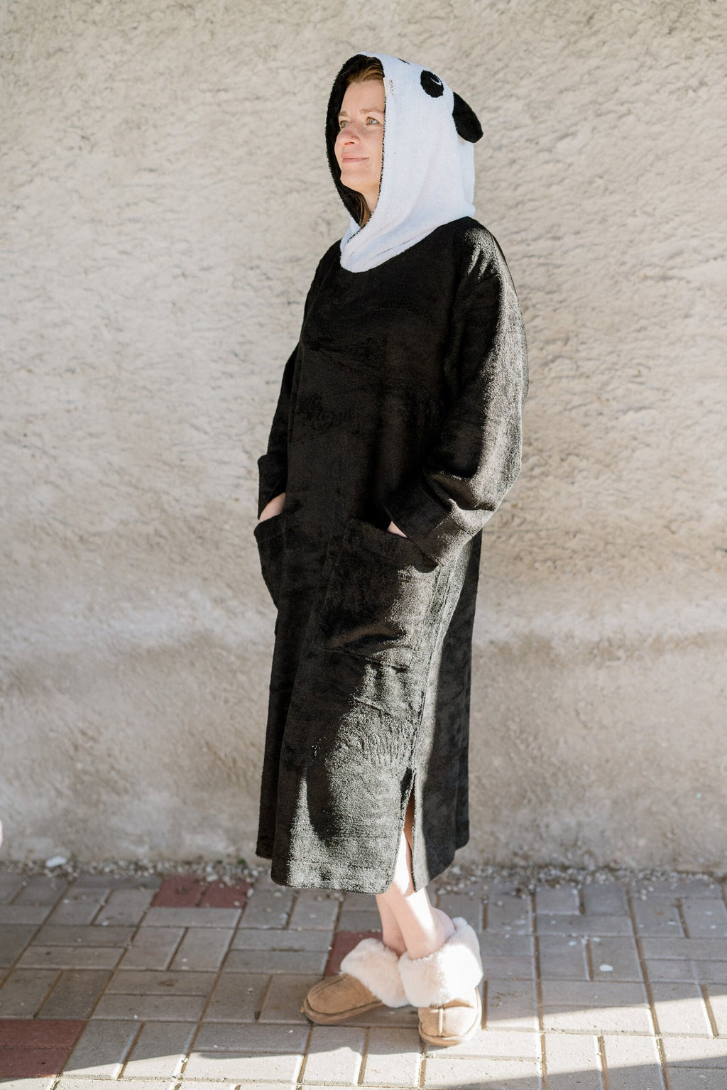 2. Unisex bamboo terry poncho by RÄTT with panda hood, worn by a woman, showcasing full length and side slits in lifestyle setting
