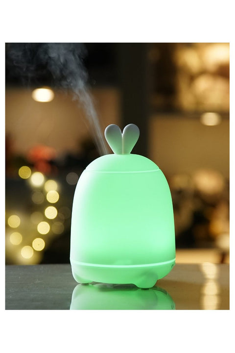 4. Green-lit Rabbit & Friends diffuser lamp with bunny ears emitting mist in a dimly lit room