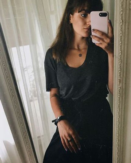 2. Woman taking a mirror selfie wearing RR Wolf Leather Bracelet in black with silver wolf buckle