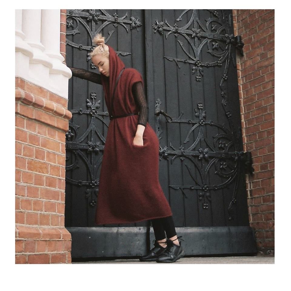 5. Women's black leather body harness by RR styled with a long red dress and black top, outdoor setting