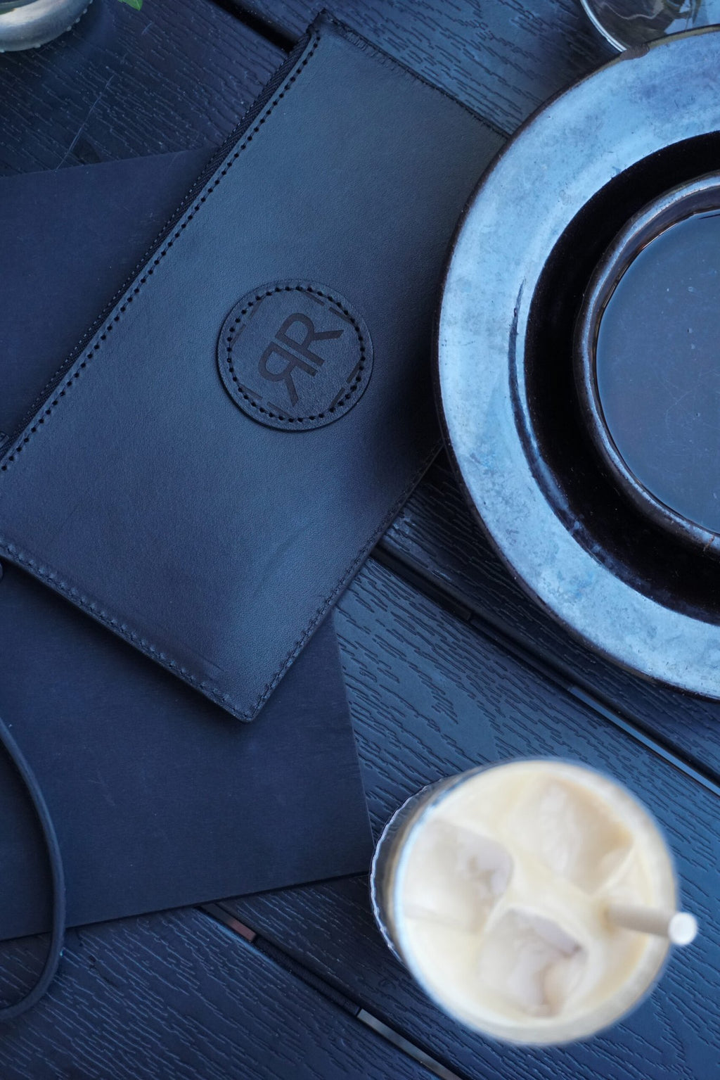 7. RR leather wristlet wallet on table with drink and plates, highlighting elegant design and logo