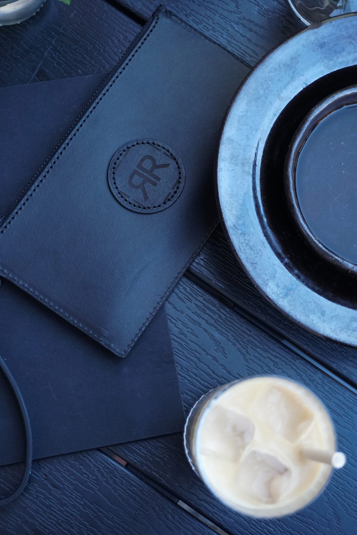 7. RR leather wristlet wallet on table with drink and plates, highlighting elegant design and logo