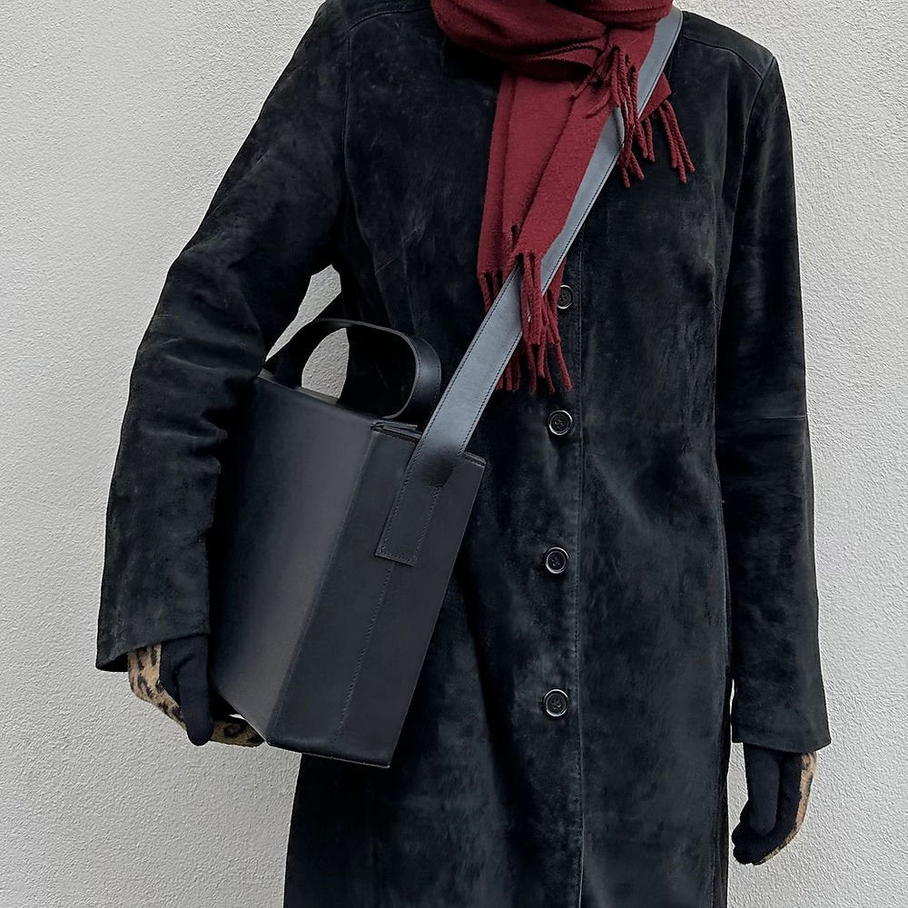 1. Women's black leather BOX Bag by RR worn crossbody with a red scarf and black coat, showcasing minimalist style