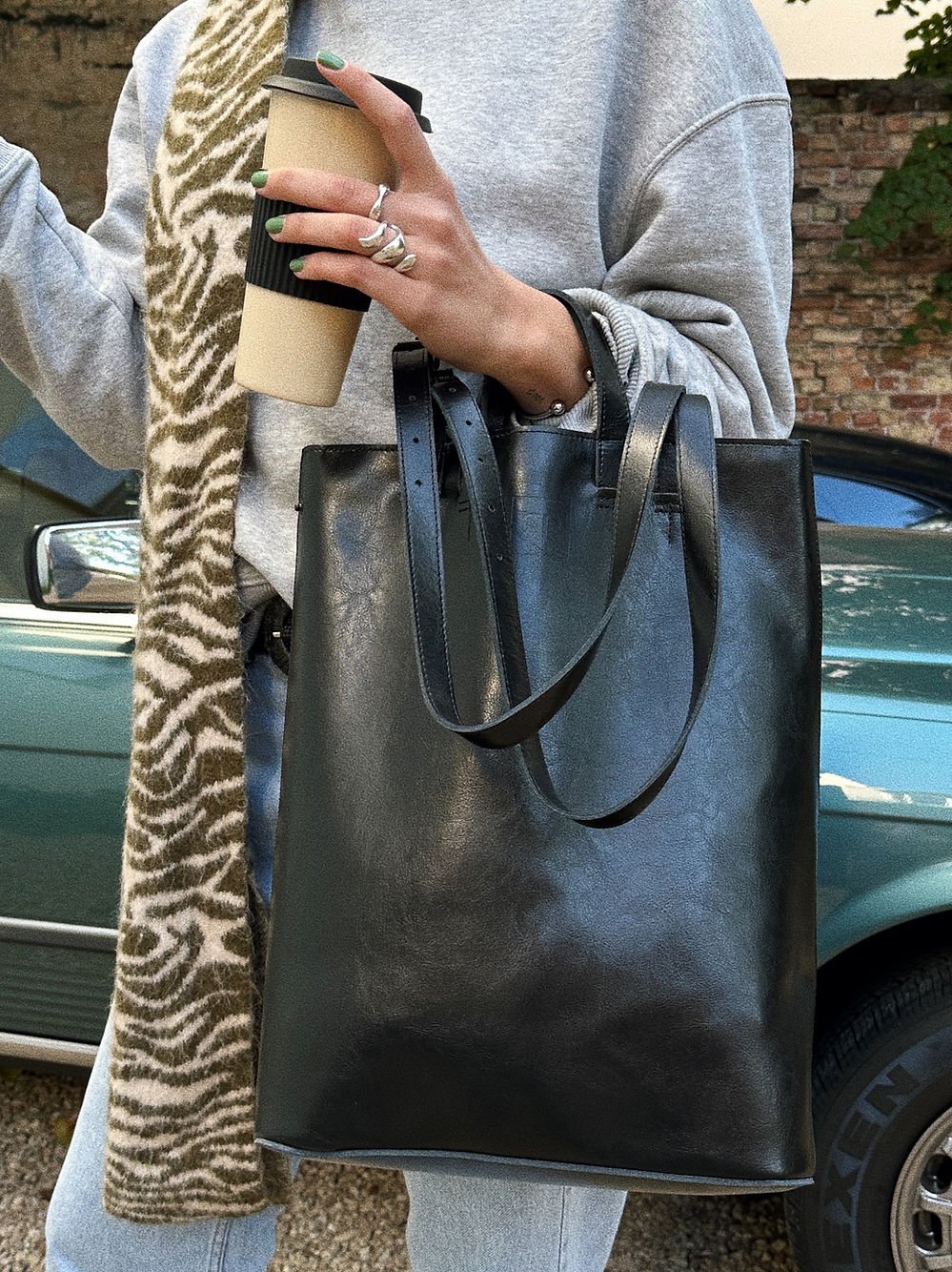7. Woman with RR structured tote bag in black, styled with casual outfit and coffee cup, near car
