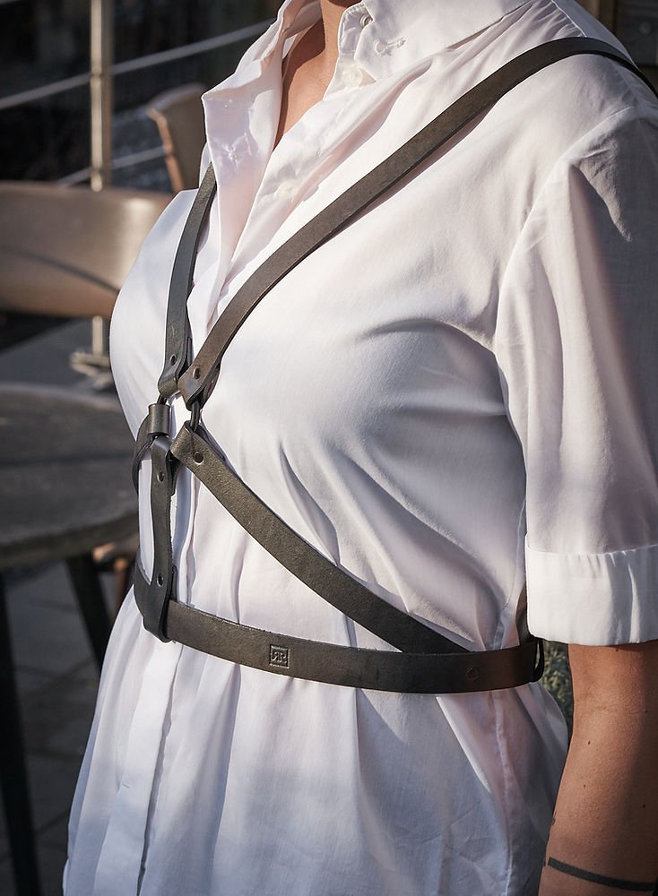 2. Close-up of women's black leather body harness by RR over white shirt, side view