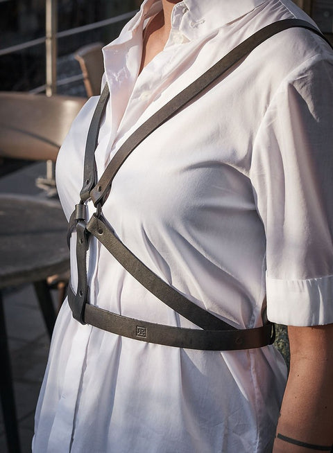 2. Close-up of women's black leather body harness by RR over white shirt, side view