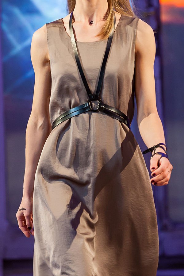 1. Women's black leather body harness by RR worn over a taupe dress, showcasing adjustable fit and buckle fastening