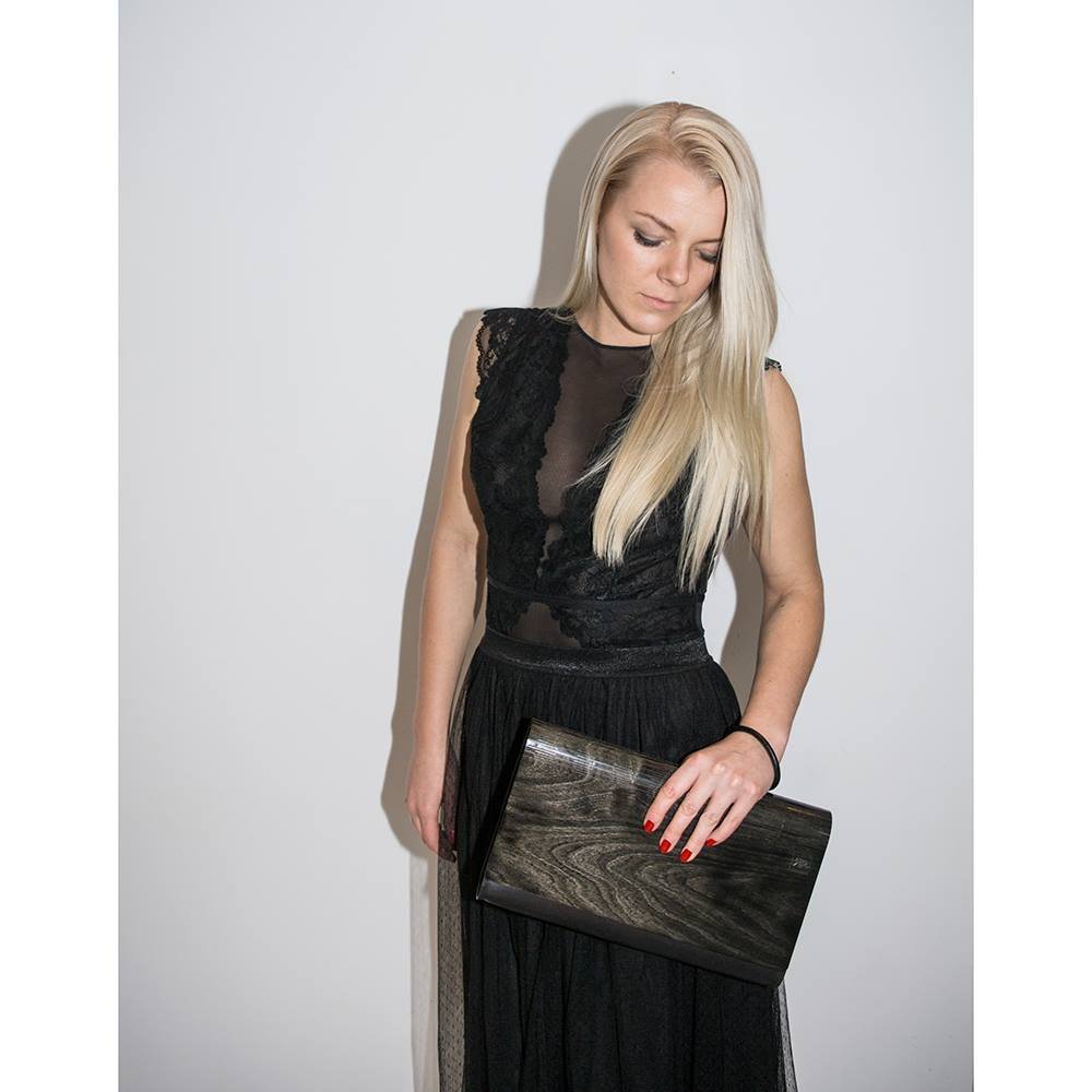 2. Woman holding large glossy wood clutch by RR, styled with a black lace dress