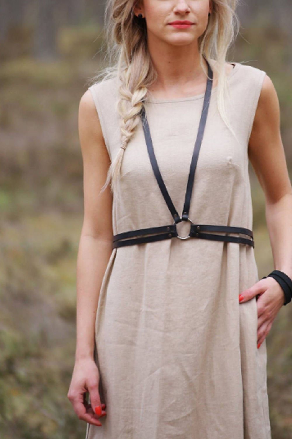 6. Woman wearing black leather body harness by RR over a beige dress in an outdoor setting, showcasing versatile style