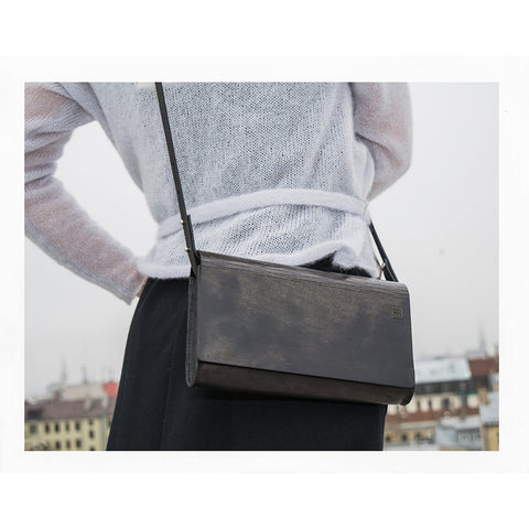 4. Large glossy wood clutch by RR worn crossbody with a white top, urban background