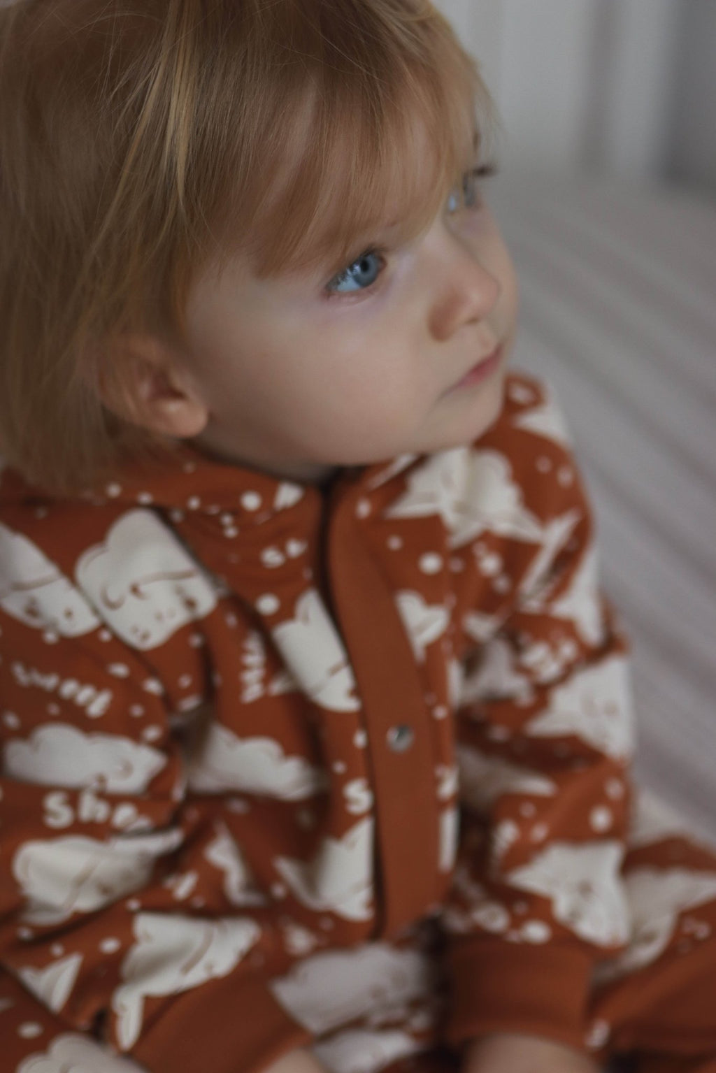 3. Close-up of baby in cinnamon sheep print jumpsuit highlighting fabric and button details