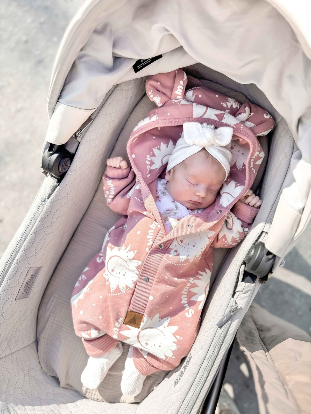 1. Baby sleeping in stroller wearing Zezuzulla pink suns eared jumpsuit with white bow headband