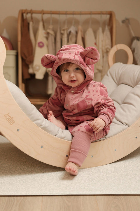 1. Baby wearing pink eared jumpsuit with lemon print sitting on wooden rocker in cozy room