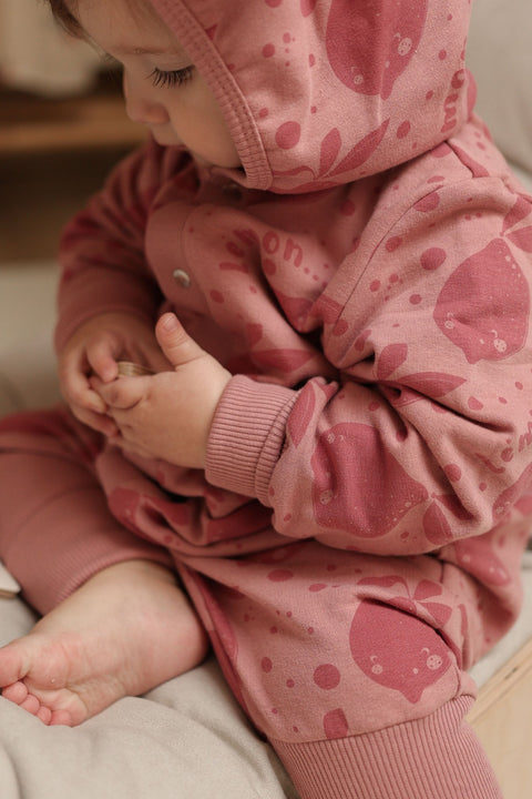 3. Close-up of baby in pink eared jumpsuit with lemon print showing fabric texture and design