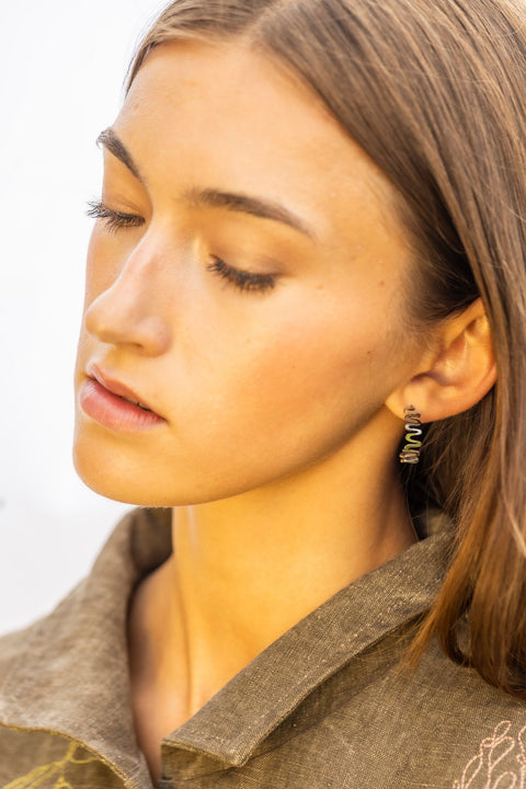 1. Woman wearing Lentsius stainless steel wavy hoop earring with high-gloss finish, eyes closed, in natural light