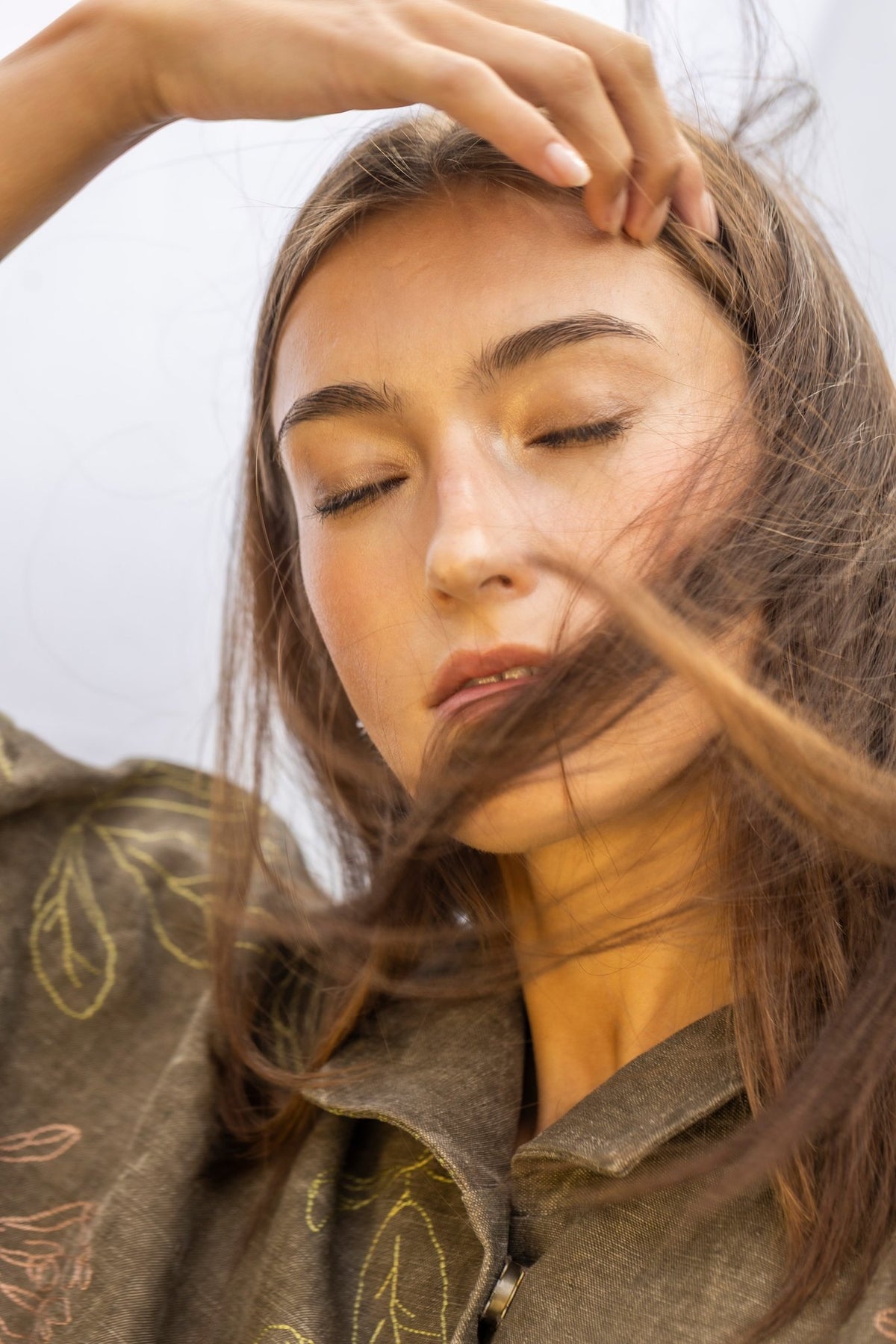 1. Woman with flowing hair wearing Lentsius stainless steel wavy hoop earring, eyes closed, in natural light