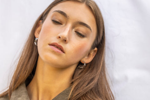1. Woman wearing Lentsius stainless steel wavy hoop earrings, eyes closed, in natural light