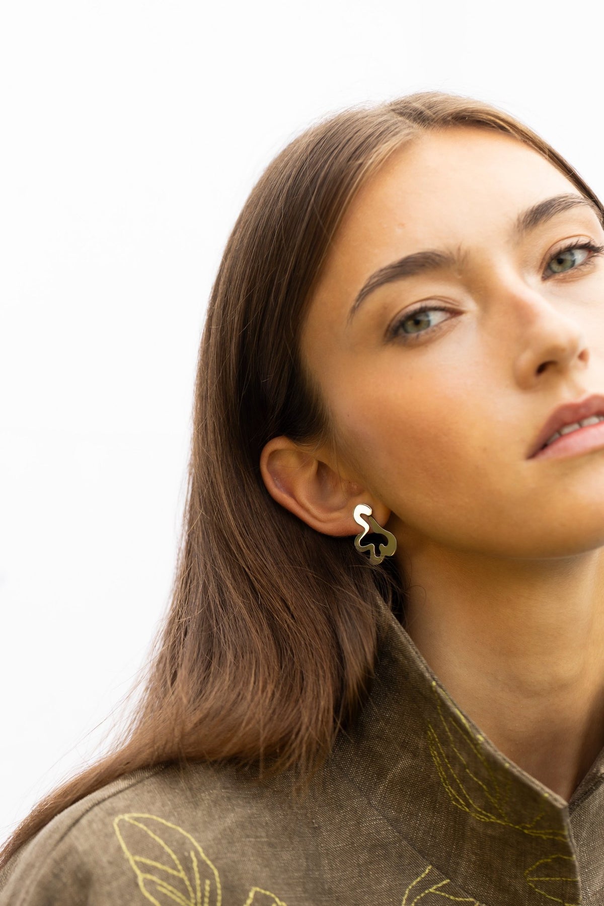 1. Woman with head tilted wearing Lentsius Folia Bold earrings, emphasizing stainless steel elegance