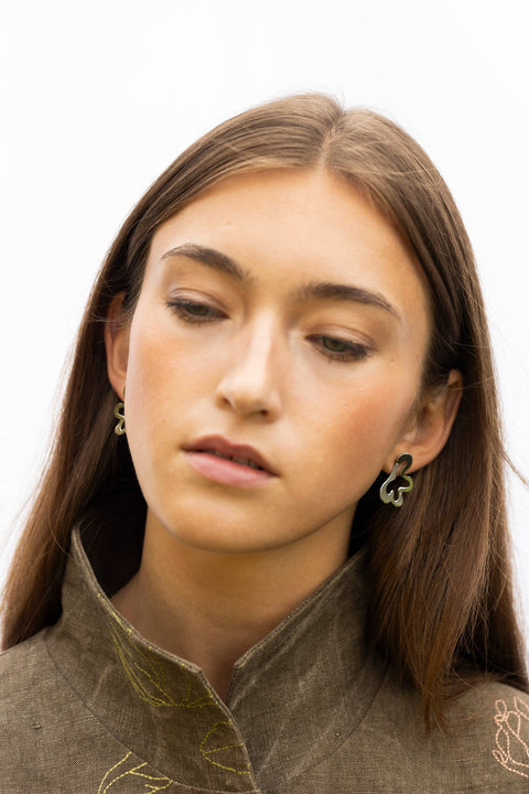 1. Woman looking down wearing Lentsius Folia Bold earrings, emphasizing high-gloss stainless steel