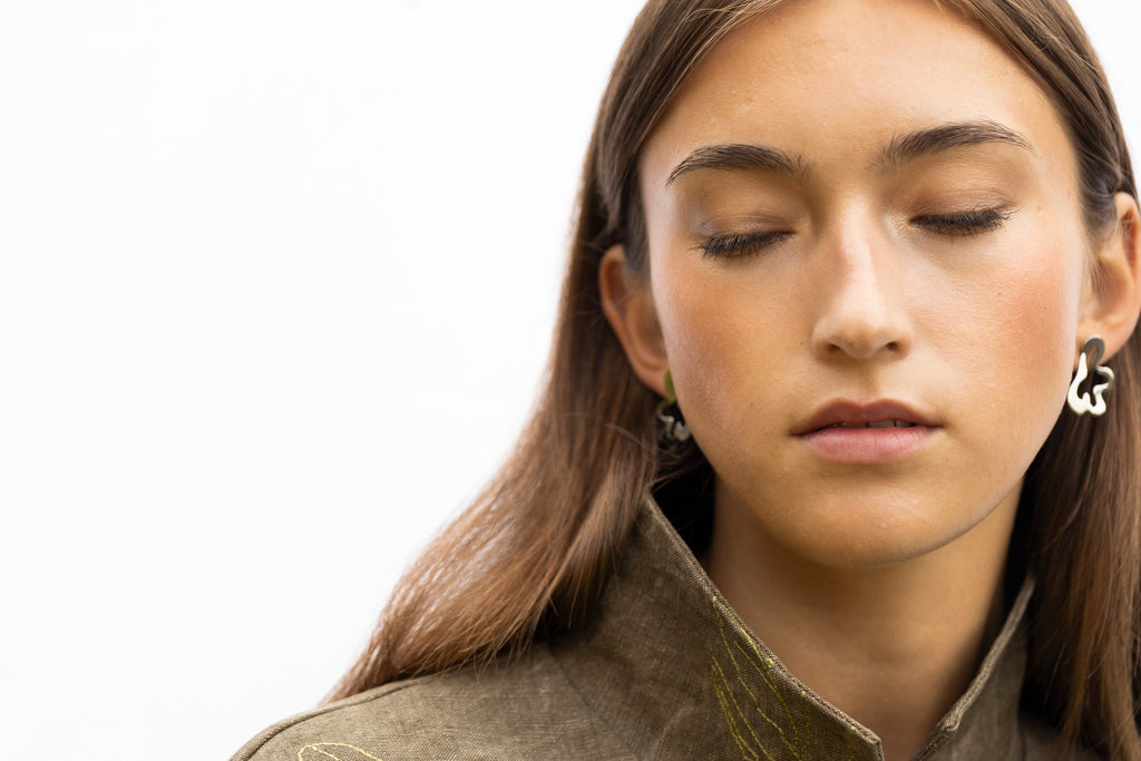 1. Woman with closed eyes wearing Lentsius Folia Bold earrings, highlighting stainless steel craftsmanship