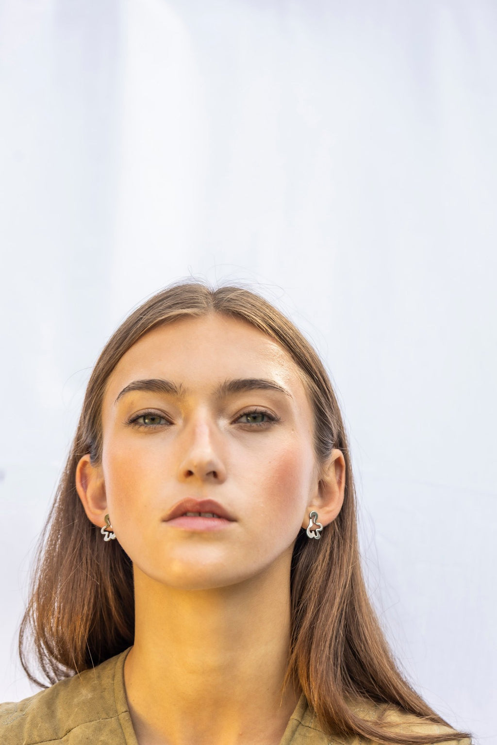 1. Woman wearing Lentsius Folia Mini earrings, facing forward with neutral expression
