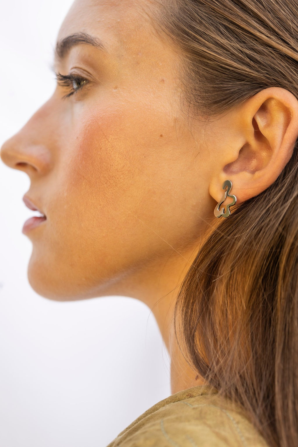 1. Woman wearing Lentsius Folia Mini earrings, side profile with soft expression