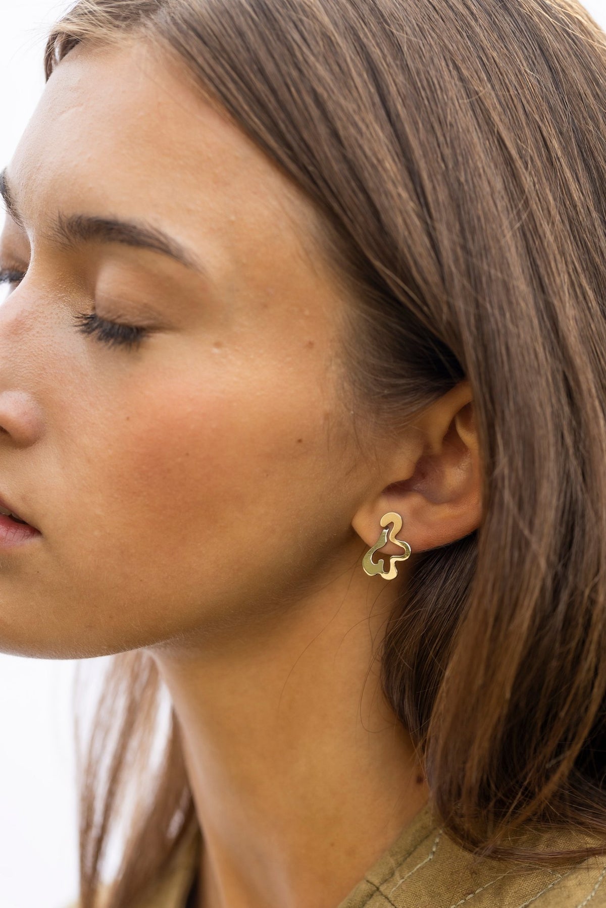 1. Woman wearing Lentsius Folia Mini earrings, side profile with relaxed expression