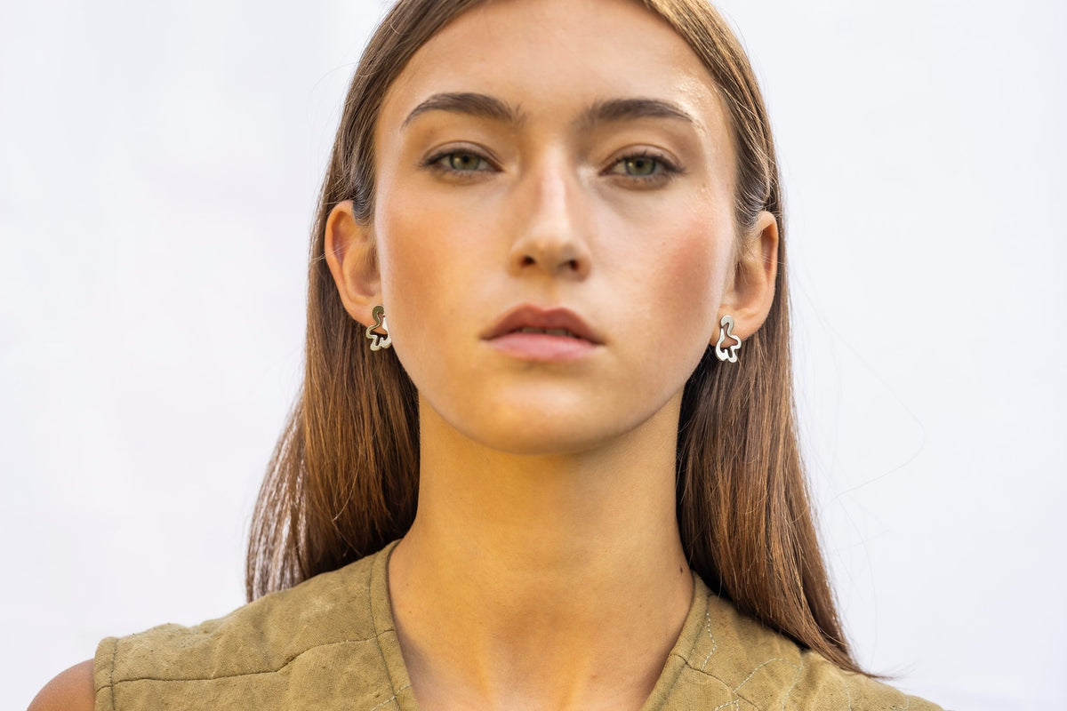 1. Woman wearing Lentsius Folia Mini earrings with polished finish, facing forward