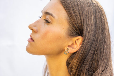1. Woman wearing Lentsius Folia Mini earrings, side profile with neutral expression