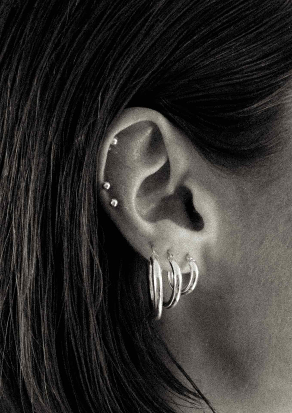 2. Close-up of women's ear adorned with multiple Ella Hoops Earrings in silver, highlighting versatile styling