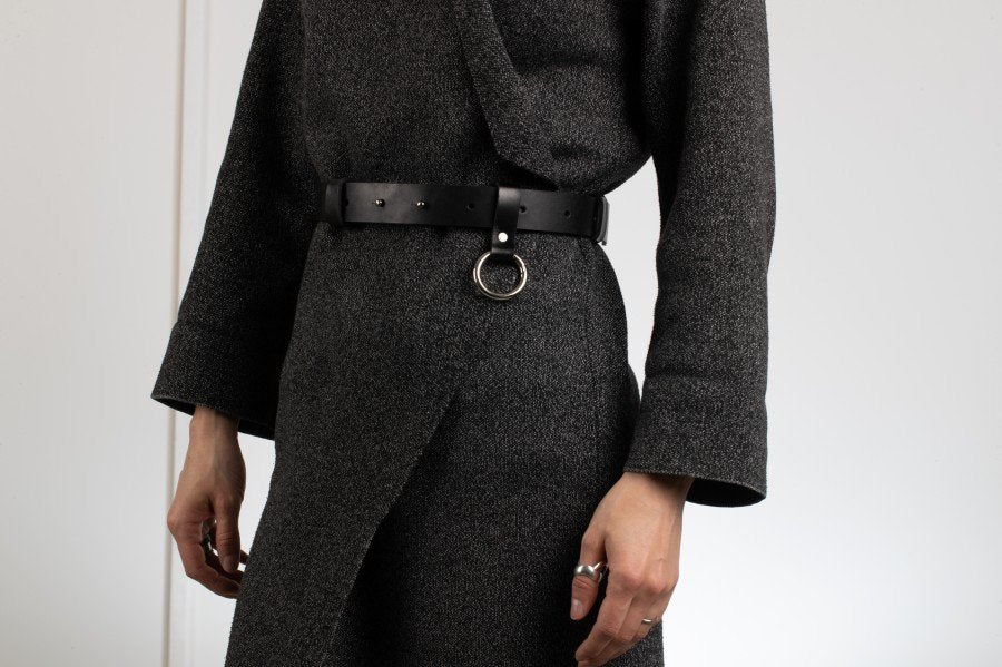 1. Unisex black leather Elon belt by PYKOK worn by model, showcasing geometric design and silver ring detail