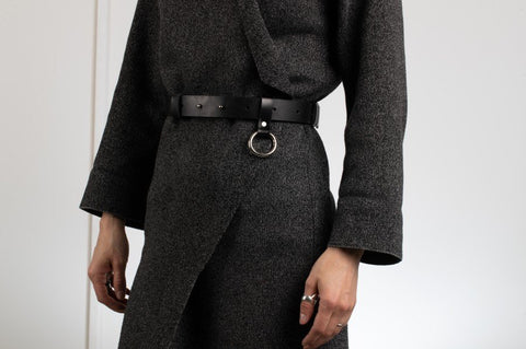 1. Unisex black leather Elon belt by PYKOK worn by model, showcasing geometric design and silver ring detail