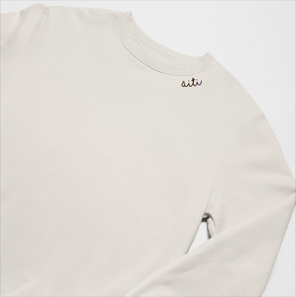 4. Unisex beige Äiti sweatshirt with embroidered collar, laid flat in studio