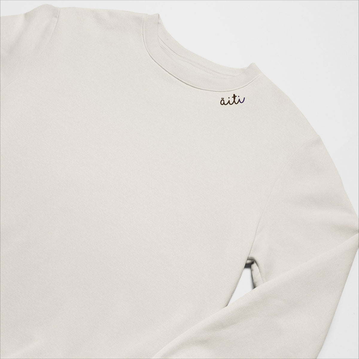 4. Unisex beige Äiti sweatshirt with embroidered collar, laid flat in studio