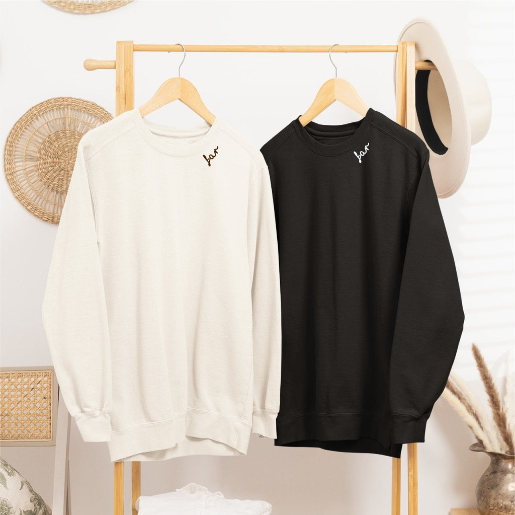 1. Beige and black unisex sweatshirts with 'far' embroidery on hangers in cozy room