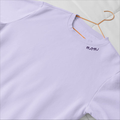 3. Lilac unisex organic cotton sweatshirt with 'Mom' embroidery on collar, laid flat on bed