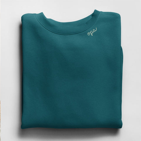 4. Flat lay of teal unisex sweatshirt with light gray 'opa' embroidery on collar