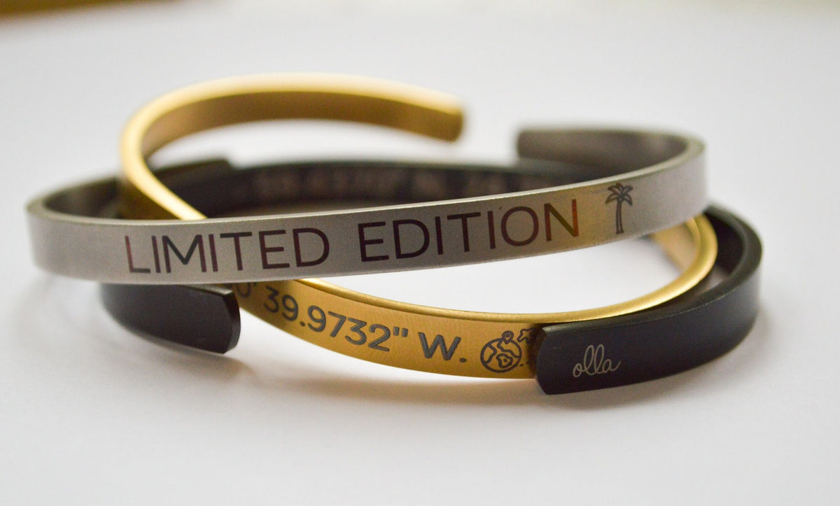 2. Two men's bracelets, one silver with 'LIMITED EDITION' text and one gold with coordinates, on a white background