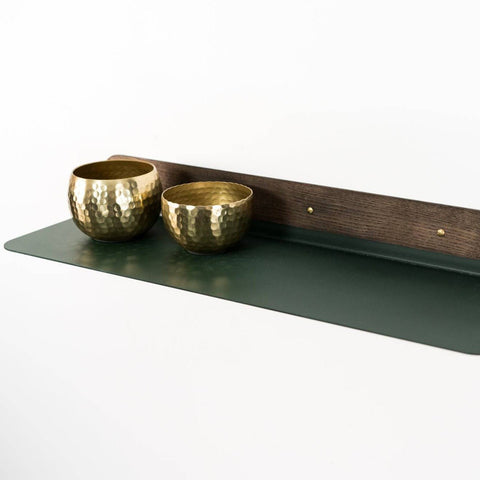 1. Green wall-mounted shelf with rounded edges holding two gold decorative bowls, by Ewart Woods