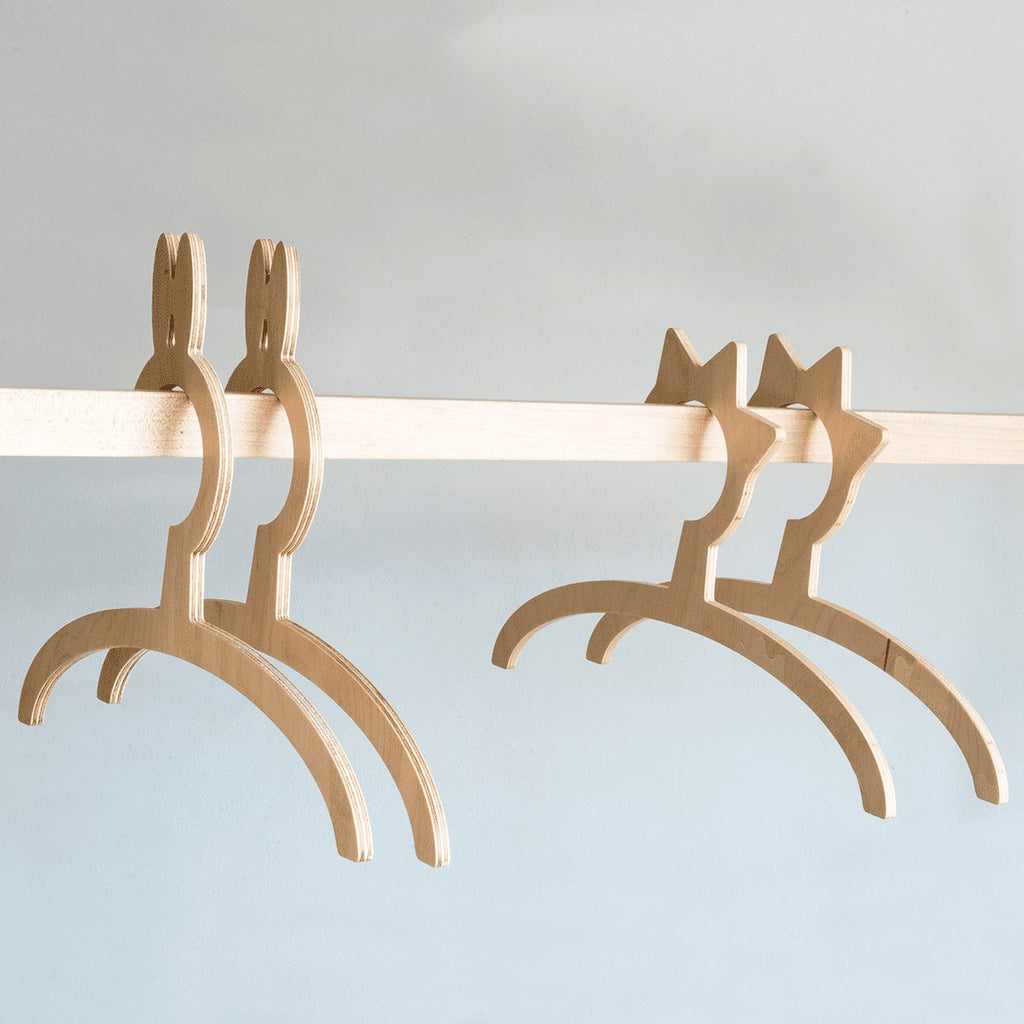 3. Detail of wooden hangers on Ewart Woods kids clothing rack with light wood bar against a neutral background