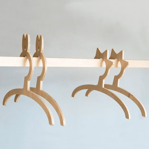 3. Detail of wooden hangers on Ewart Woods kids clothing rack with light wood bar against a neutral background