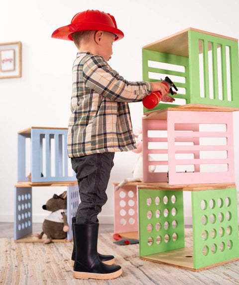 4. Side view of child in plaid shirt and red hat playing with stacked Ewart Woods storage cubes