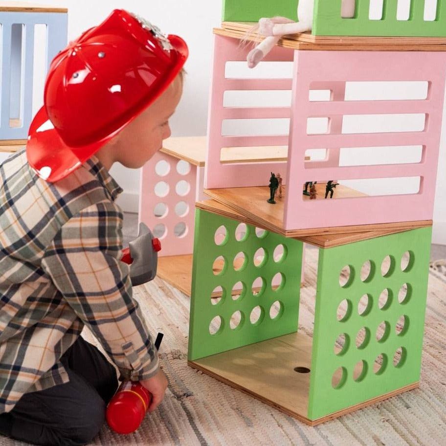 5. Child in red firefighter hat kneeling by colorful Ewart Woods storage cubes with toy soldiers inside